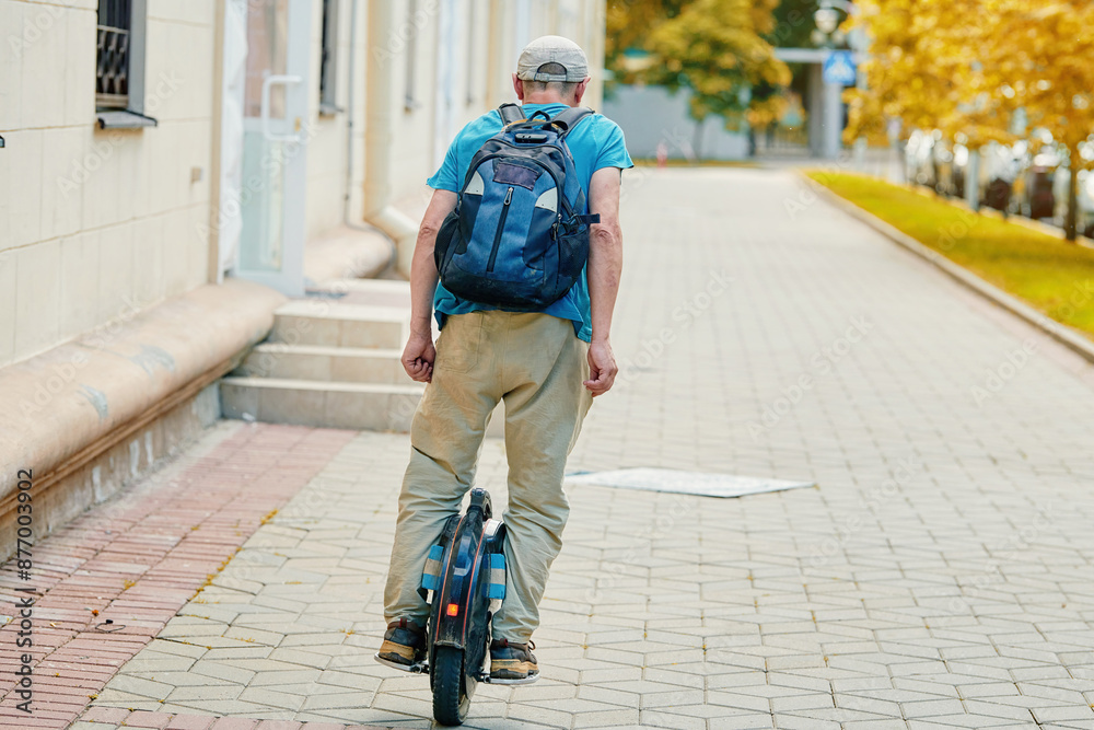 Obraz premium Active senior enjoying ride on electric unicycle in the city. One-wheel electric vehicle. Elderly man embracing eco-friendly travel on electric unicycle. Modern mobility (EUC)..