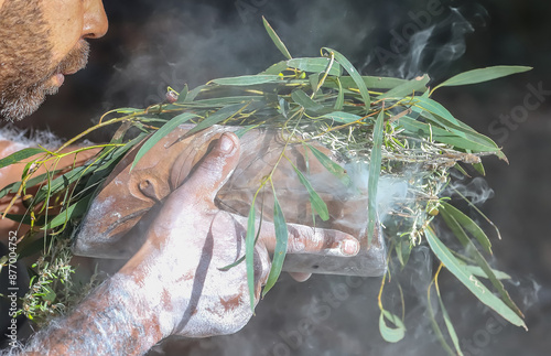 Human hands with green branches, wooden ritual dish and fire, Australian aboriginal smoking ceremony, indigenous event