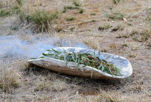 Aboriginal wooden ritual dish with green branches, Australian indigenous smoking ceremony, ritual welcome to country