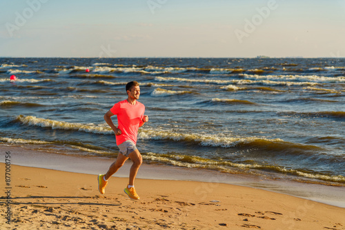 A man in a bright shirt runs along the shoreline, showcasing fitness and vitality against the backdrop of lively waves.