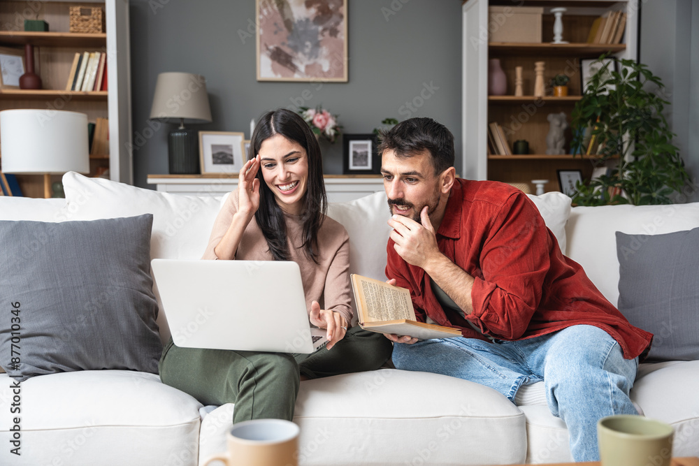 Simple living Young engaged couple sitting at home, spending quality time, woman searching for wedding dress on laptop, man reading a book, organizing wedding ceremony. Searching honeymoon destination Simple living Young engaged couple sitting at home, spending quality time, woman searching for wedding dress on laptop, man reading a book, organizing wedding ceremony. Searching honeymoon destination
