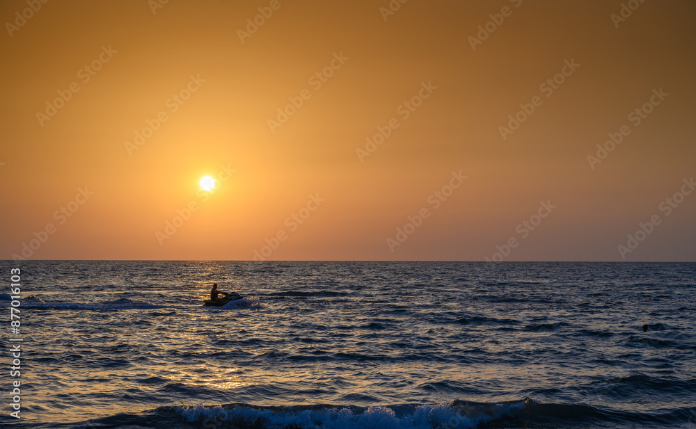 Obraz premium Calm sea with sunset sky and sun through the clouds over