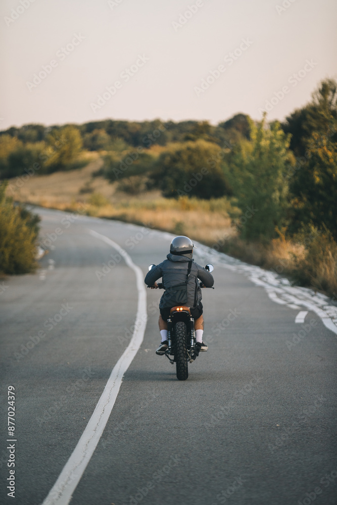 A biker rides a cafe racer on the highway A biker rides a cafe racer on the highway