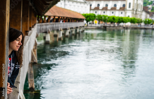 Side view of beautiful young woman leaning on bridge while thinking about life. Lucerne. Chapel bridge