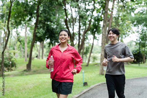 Young Couple Jogging in a Park on a Sunny Day, Staying Fit and Healthy with Smiles and Water Bottles