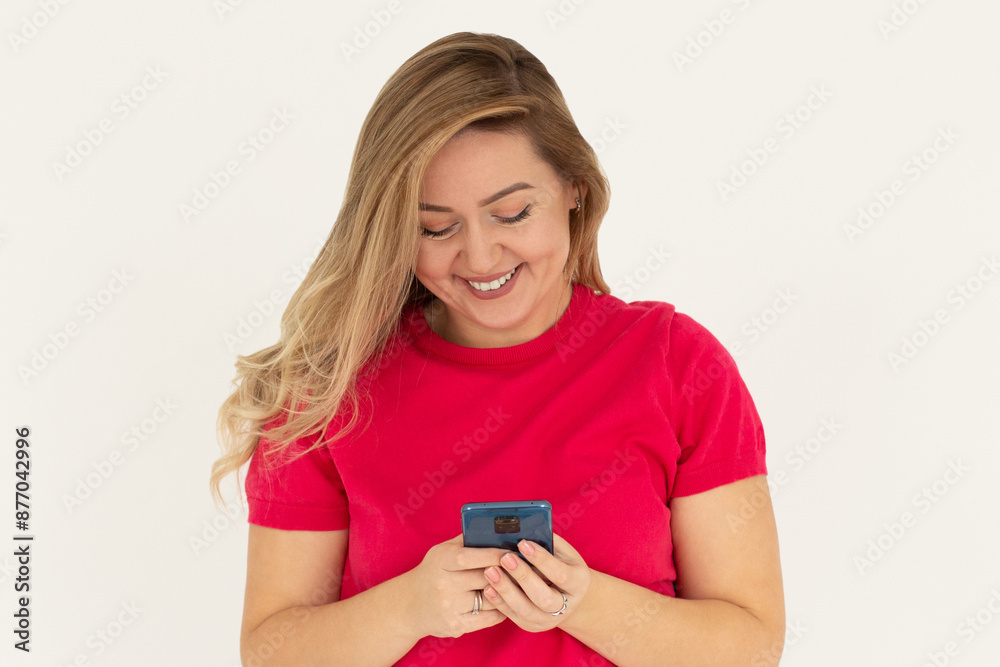 Happy pretty young woman model holding smartphone looking at cell texting message, smiling girl using mobile apps on cell phone standing isolated on white background with cellphone.