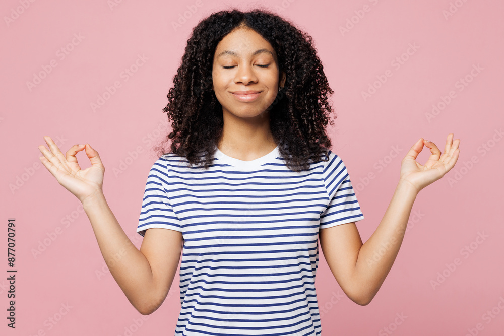 Little kid teen girl wears blue striped t-shirt casual clothes hold hands in yoga om aum gesture relax meditate try to calm down isolated on plain pastel pink background. Childhood lifestyle concept. Little kid teen girl wears blue striped t-shirt casual clothes hold hands in yoga om aum gesture relax meditate try to calm down isolated on plain pastel pink background. Childhood lifestyle concept.