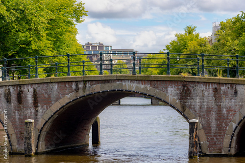 Canvas Print Summer cityscape, Canals of Amsterdam, Under view of brick bridge and railing, Still water and soft sunlight in the afternoon, Canal cruises is very famous activities, Tourist attraction, Netherlands