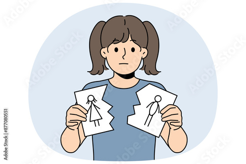 Sad little girl is nervous about parents divorce and is holding torn drawing of mom and dad. Sad child suffers after learning about dissolution of marriage between mother and father