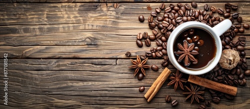 Wooden table background with a coffee cup filled with coffee beans, cinnamon, and star anise, providing an appealing copy space image.