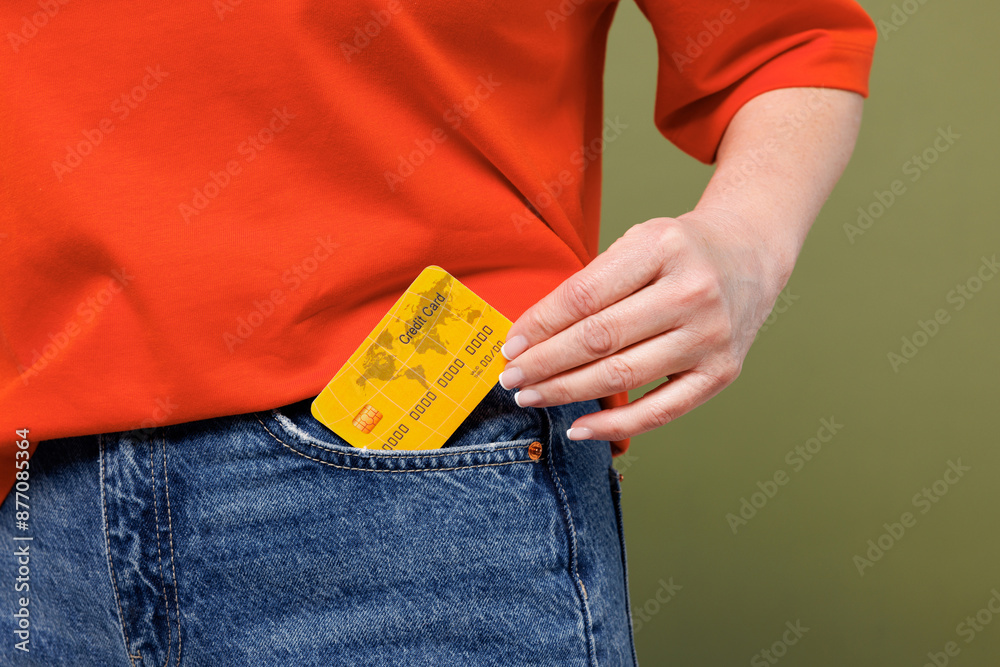 Φωτογραφία Cropped close up woman she wearing orange t-shirt casual clothes hold in hand put into pocket mock up of credit bank card isolated on plain pastel green background studio portrait
