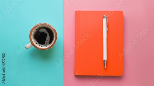 Orange note book white pen and cup of coffee isolated on pink and blue background photo