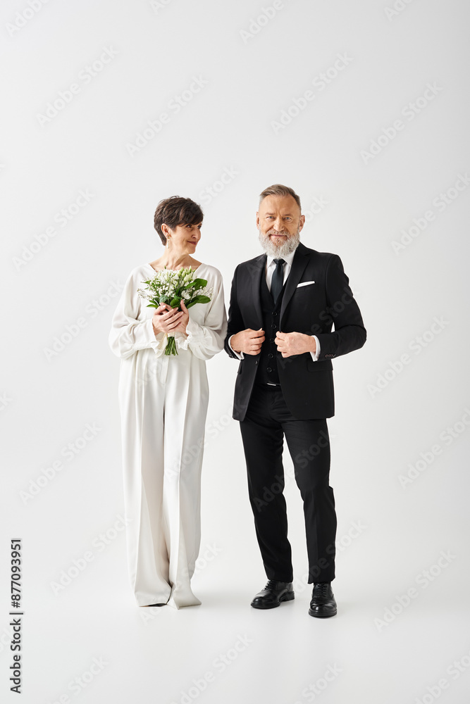 Middle-aged bride and groom in formal attire stand together in a studio, celebrating their special day with love and elegance. Middle-aged bride and groom in formal attire stand together in a studio, celebrating their special day with love and elegance.
