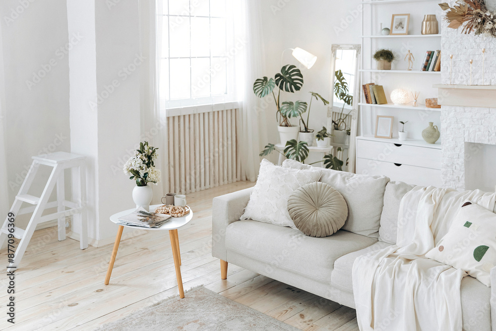 Scandinavian style sofa with plaid and pillows and coffee table in modern stylish bright living room with large windows, fireplace, shelving and potted plants. Nobody Scandinavian style sofa with plaid and pillows and coffee table in modern stylish bright living room with large windows, fireplace, shelving and potted plants. Nobody