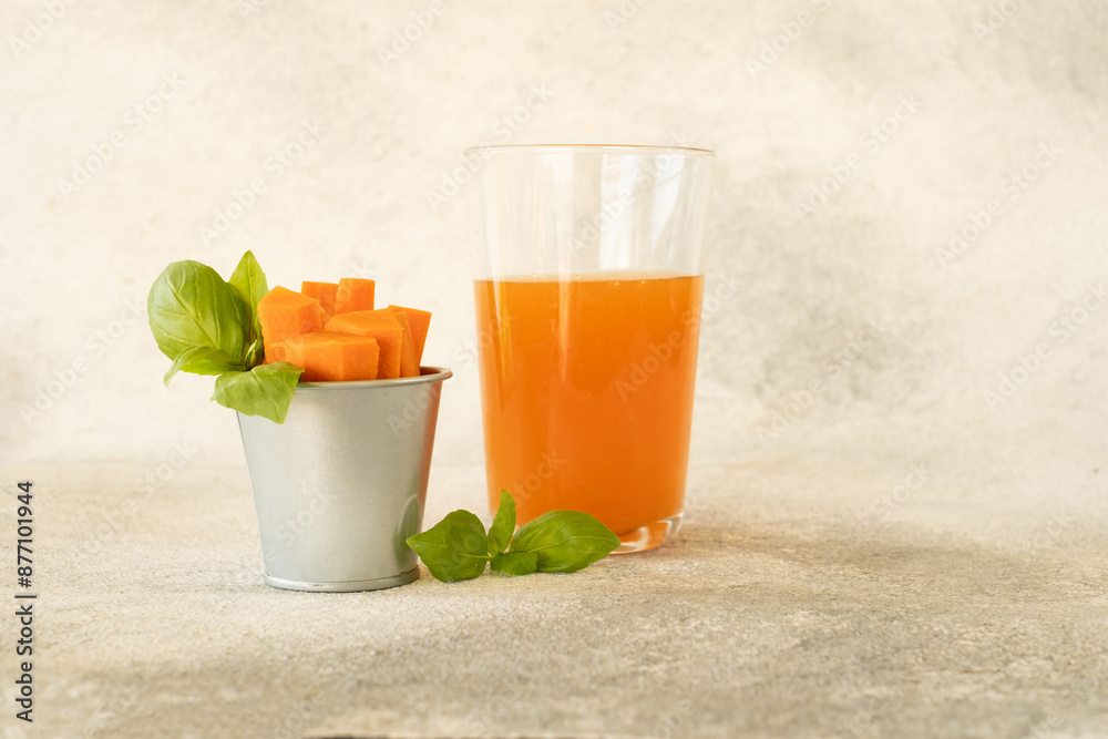 Fototapeta premium Carrot juice in a glass and fresh carrots with leaves