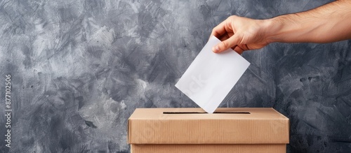 Hand inserting a ballot into a box on a neutral-grey background with a generous copy space image. photo