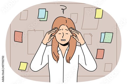 Tired businesswoman stands near blackboard with notes and grabs head after learning about overdue deadline. Woman manager feeling headache due to regular overtime caused by strict deadline