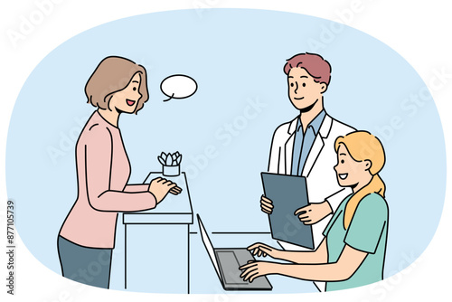 Woman client of clinic stands near reception desk and consults with doctor or chooses convenient time for next appointment. Employees of cosmetology clinic and potential patient are in lobby