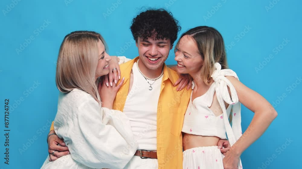 Group of young three stylish friends posing in studio. Fashion man and two cute female dressed in casual summer clothes. Smiling models having fun. Cheerful women and guy isolated on blue chromakey Group of young three stylish friends posing in studio. Fashion man and two cute female dressed in casual summer clothes. Smiling models having fun. Cheerful women and guy isolated on blue chromakey