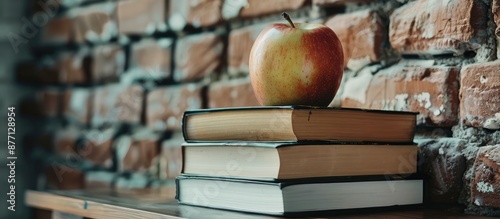 Education concept depicted by textbooks and an apple on a desk against a school brick wall background, including copy space image. photo