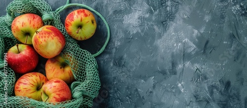 Fresh apples in a green mesh bag, showcasing a zero waste, eco-friendly, or plastic-free lifestyle concept, with a copy space image. photo