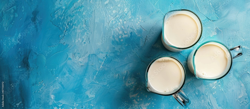 Top view of a jug and glass of milk on a blue backdrop with copy space image. Top view of a jug and glass of milk on a blue backdrop with copy space image.