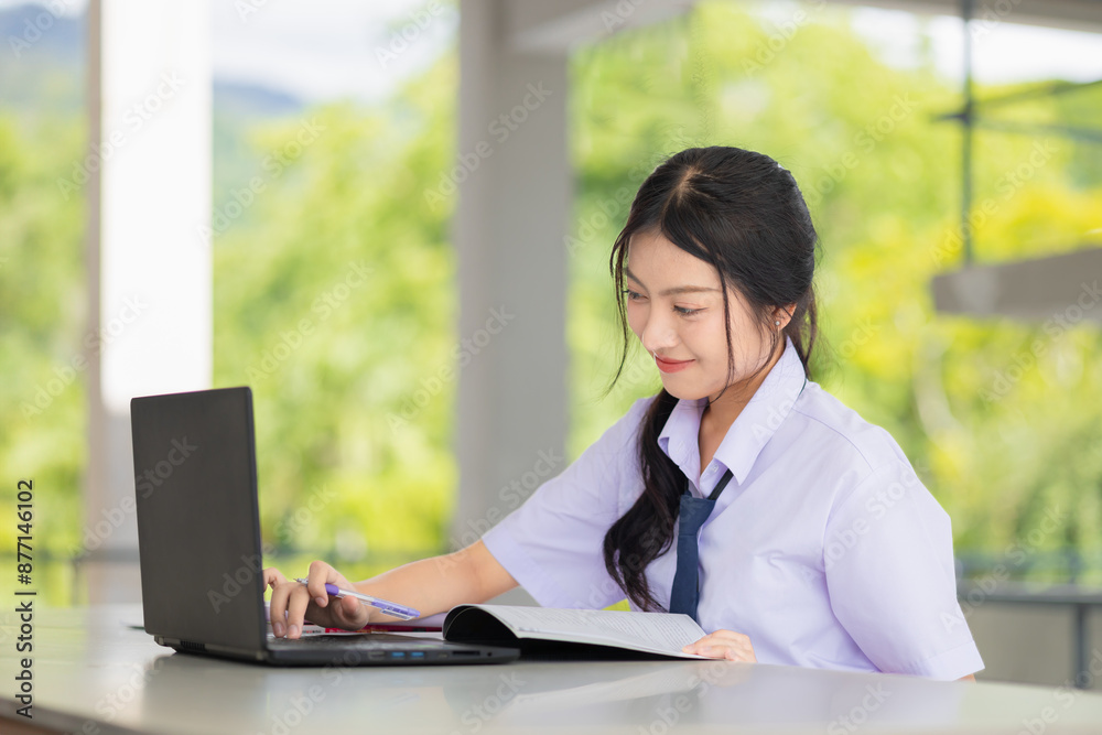 happy school uniform teen girl using laptop computer to do homework learning education in school campus, self education technology concept. happy school uniform teen girl using laptop computer to do homework learning education in school campus, self education technology concept.