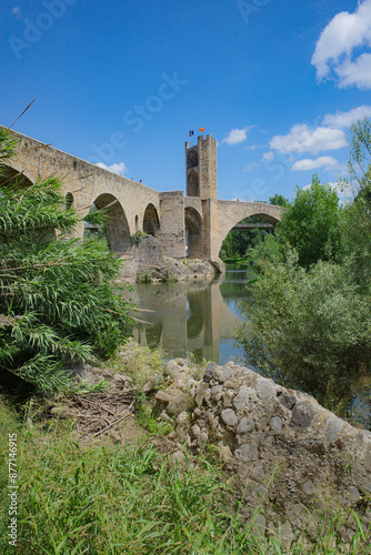 Girona, Spain - 7 July, 2024: Reflections of the medieval Pont Vell bridge on the River Fluvia at Besalu, Catalonia photo