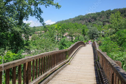 Girona, Spain - 7 July, 2024: Wooden footbridge on the River Fluvia in Castellfollit de la Roca, Catalonia photo