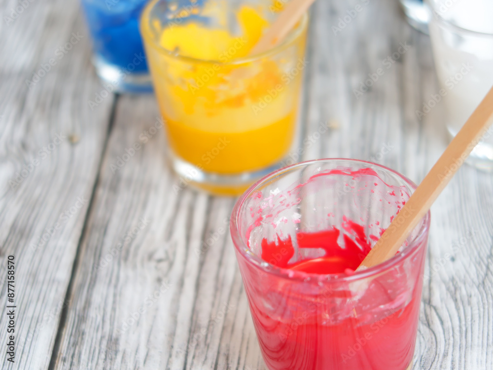 CMYK pigments in glass cups: cyan, magenta, yellow, black and white dyes and wood sticks for mixing DIY. CMYK pigments in glass cups: cyan, magenta, yellow, black and white dyes and wood sticks for mixing DIY.