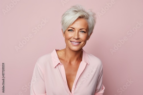 Portrait of beautiful middle aged woman looking at camera and smiling while standing against pink background