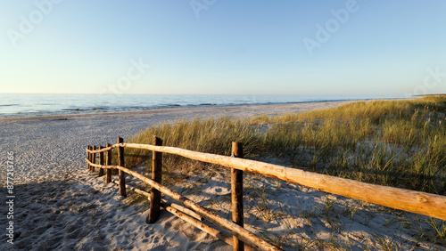 Obraz na płótnie Beautiful wide beach on the Baltic Sea in the setting sun. Entrance to the beach. Wooden balustrade. Dunes covered with grass. Słaszczewo, Poland w salonie