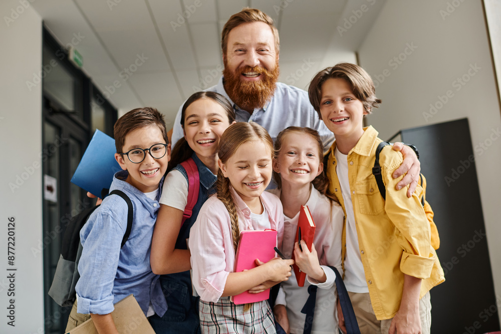 A man teacher engages with a diverse group of children in a lively hallway, imparting knowledge and guidance in a bright educational environment. A man teacher engages with a diverse group of children in a lively hallway, imparting knowledge and guidance in a bright educational environment.