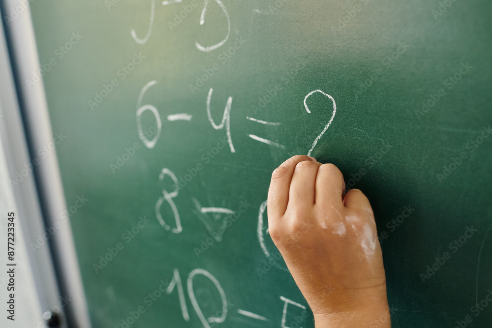 kid writes on a blackboard with white chalk in lively classroom setting, math kid writes on a blackboard with white chalk in lively classroom setting, math