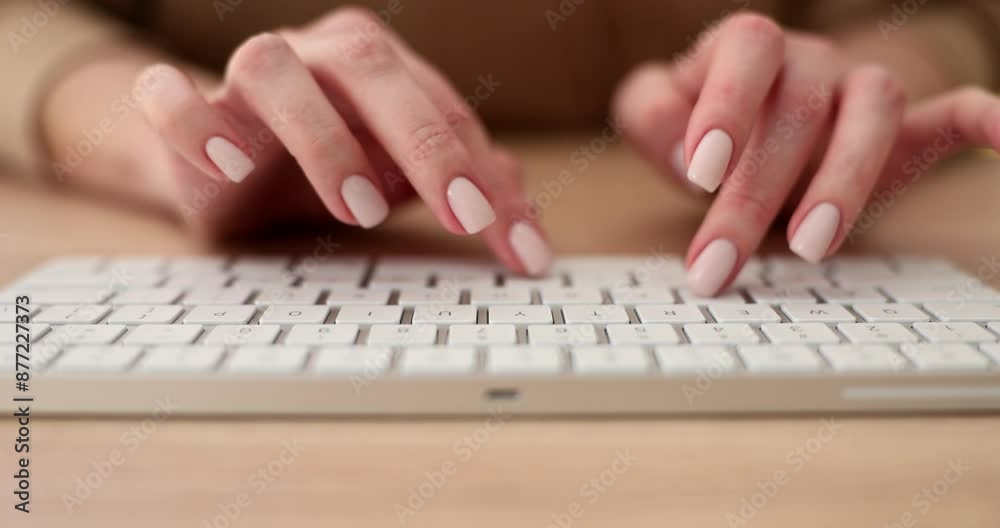 Hands of woman with neat manicure typing on white keyboard sitting at wooden table. Female freelancer writes article on computer slow motion