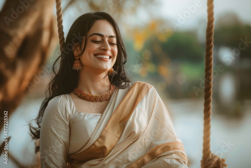 Joyful woman wearing ethnic Indian traditional dress sitting on a swing in the outdoor photo