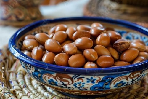 Closeup of argan seeds in a painted ceramic bowl on a woven mat, symbolizing moroccan beauty rituals photo