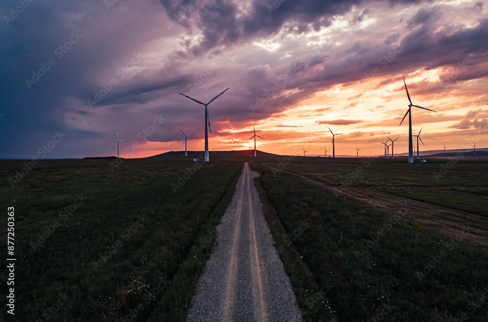 Obraz premium Wind turbines at sunset on a rural road