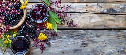 Ripe elderberries and dried flowers crafted into sweet jam syrup or confiture offering a healthy dessert or hot drink option on an old wooden table with ample copy space image