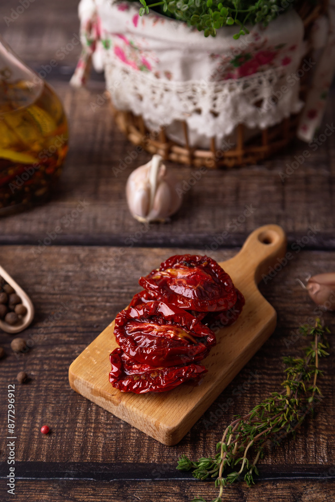 Sun-dried tomatoes in olive oil on a mini board with pepper, garlic and thyme in a rustic style. Selective focus, close-up. Sun-dried tomatoes in olive oil on a mini board with pepper, garlic and thyme in a rustic style. Selective focus, close-up.