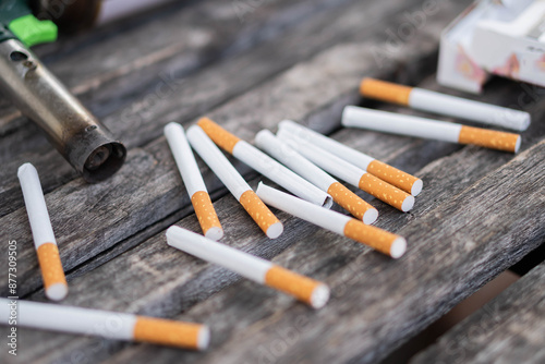 Scattered cigarettes and lighter on wooden surface photo