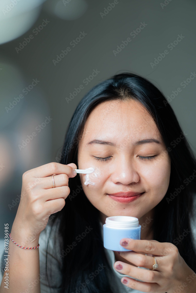 Woman applying face cream with a small spatula Woman applying face cream with a small spatula