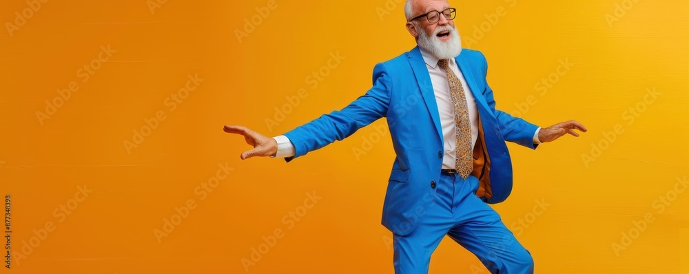 Elderly man in a blue suit dancing against a vibrant orange background. Free copy space for banner.