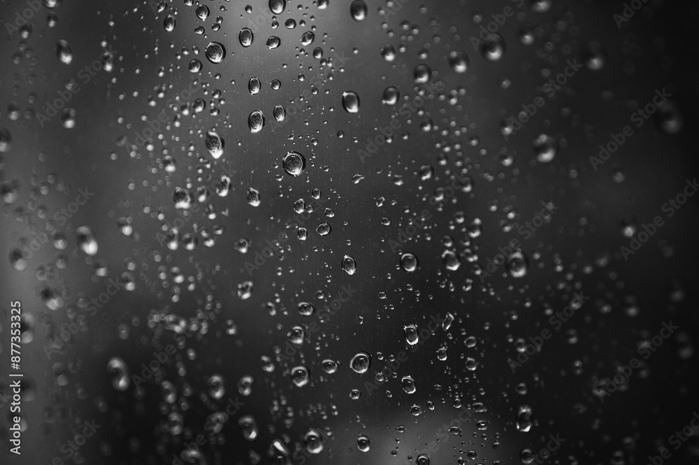 Obraz premium black and white photo, background of raindrops on glass, cloudy day with sunbeam, selective focus