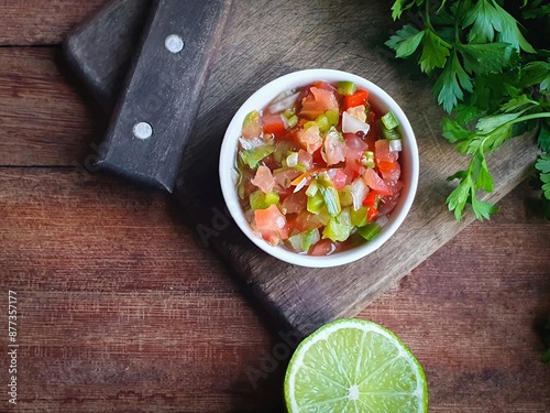 vinaigrette sauce tomatoes, peppers and onion in a white pot on a wooden background typical of a Brazilian barbecue
