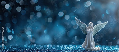 A simple holiday theme featuring a white angel centerpiece against a dark blue glitter backdrop with focus on the angel allowing for a blank area in the image. Copy space image photo