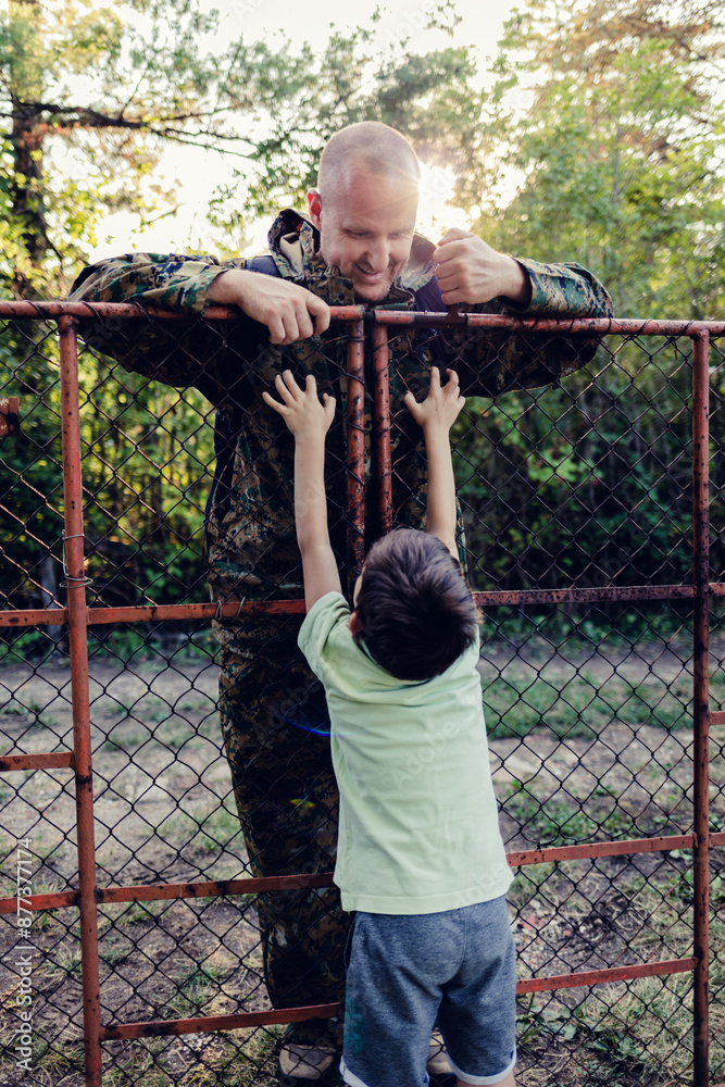 Obraz premium Happy military father in uniform returning to family. An overjoyed boy is waiting to hug his dad who is returning after military service.