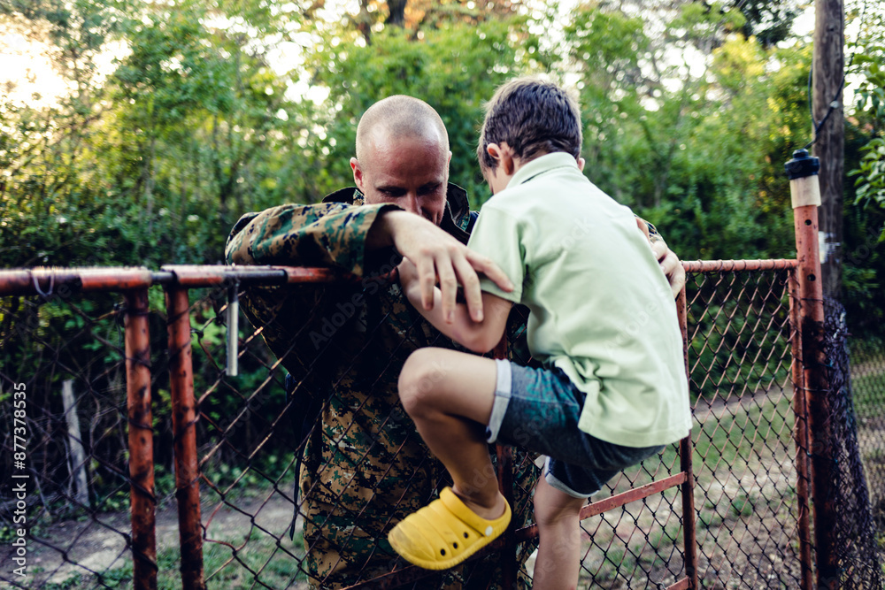 Naklejka premium Happy military father in uniform returning to family. An overjoyed boy is waiting to hug his dad who is returning after military service.
