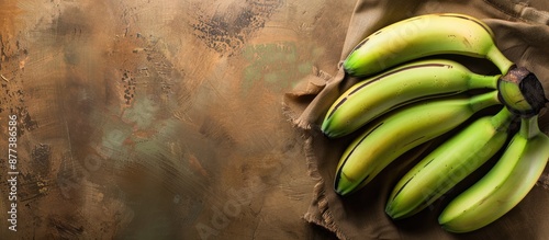 Green unripe bananas showcased on a warm toned brown backdrop with ample copy space image photo