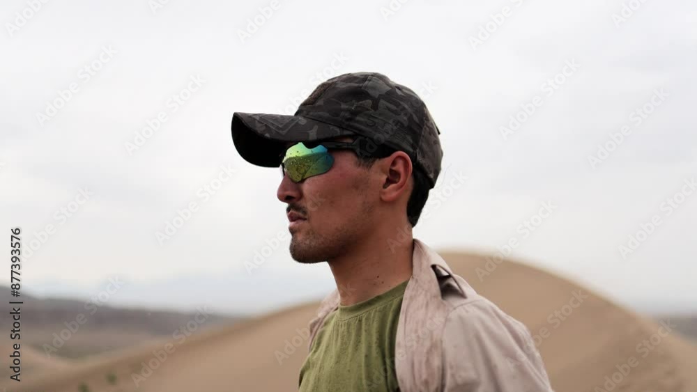 A man hikes up the Singing Dunes in the Altyn-Emel National Park, Kazakhstan. The vast desert landscape stretches behind him, with rolling dunes and distant mountains shrouded in mist. A man hikes up the Singing Dunes in the Altyn-Emel National Park, Kazakhstan. The vast desert landscape stretches behind him, with rolling dunes and distant mountains shrouded in mist.